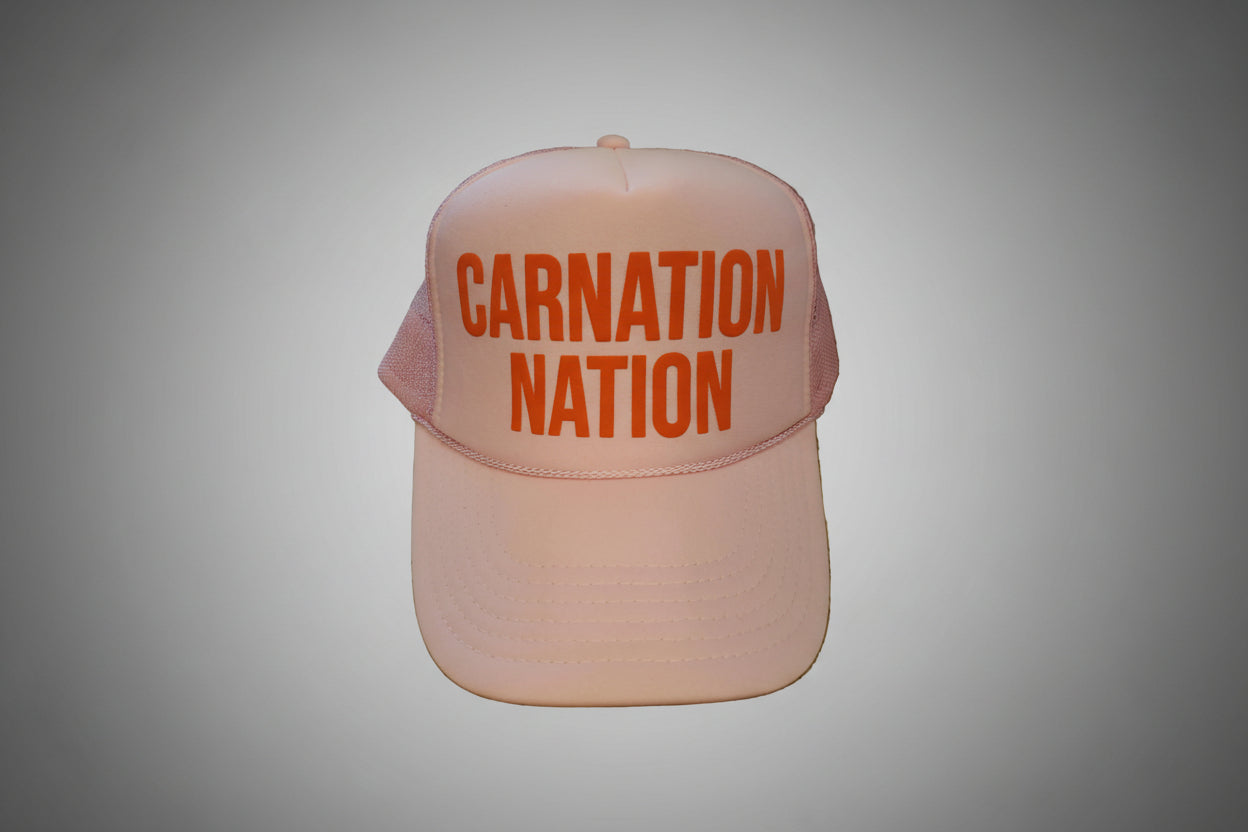 Pink cap with 'Carnation Nation' text on a wooden surface