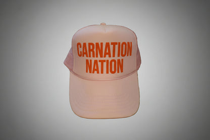 Pink cap with 'Carnation Nation' text on a wooden surface