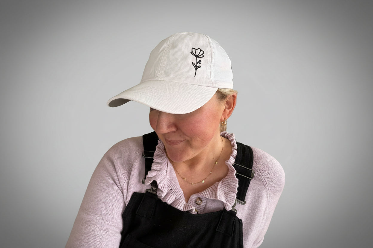 A person wearing a classic white embroidered baseball cap with a floral design.