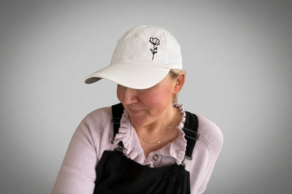 A person wearing a classic white embroidered baseball cap with a floral design.